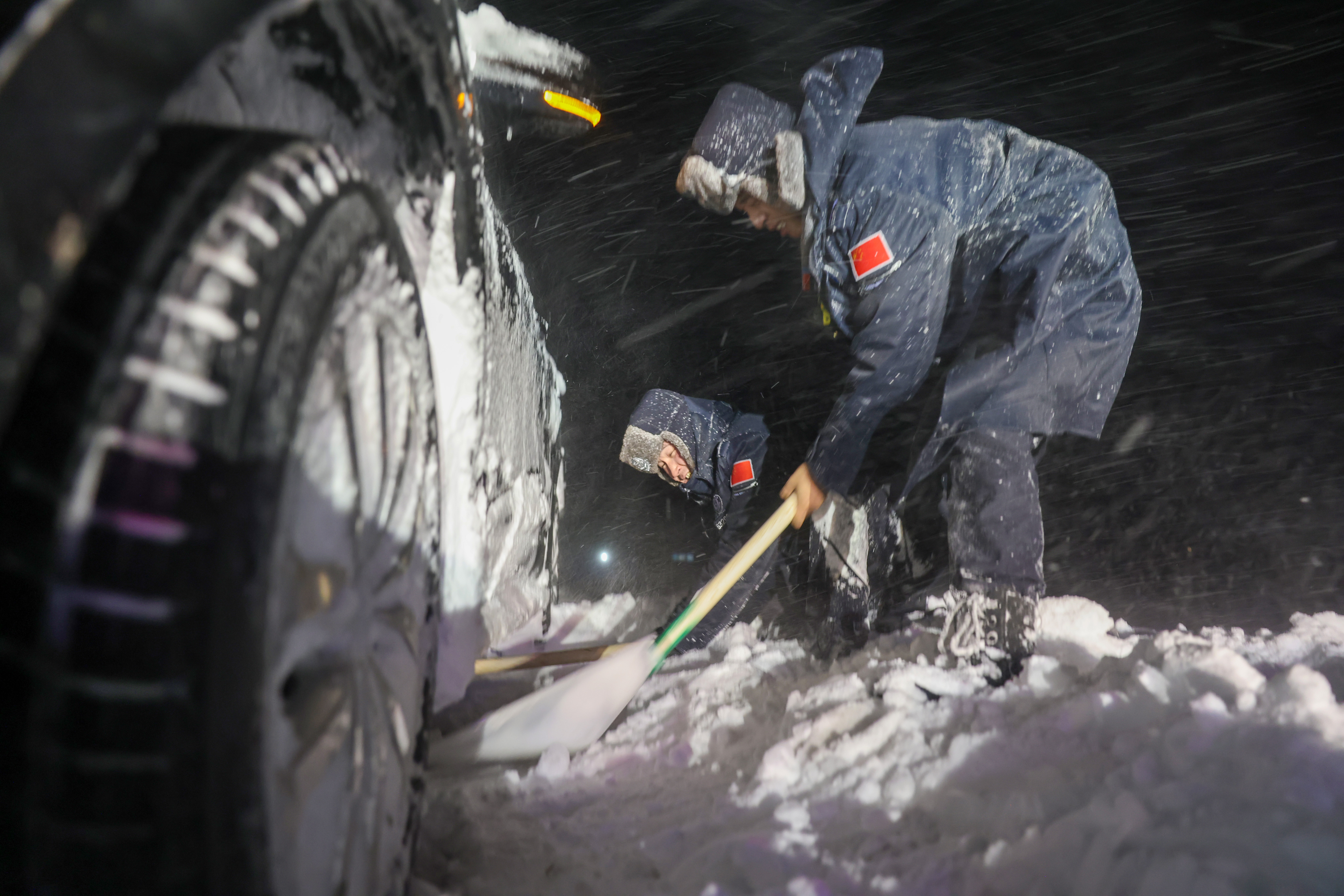 6图为 2025年11月13日,新疆阿勒泰边境管理支队吐尔洪边境派出所民警正在清理被困车辆周边的积